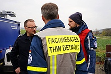 Drei Einsatzkräfte von THW und Feuerwehr besprechen sich.