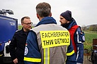 Drei Einsatzkräfte von THW und Feuerwehr besprechen sich.